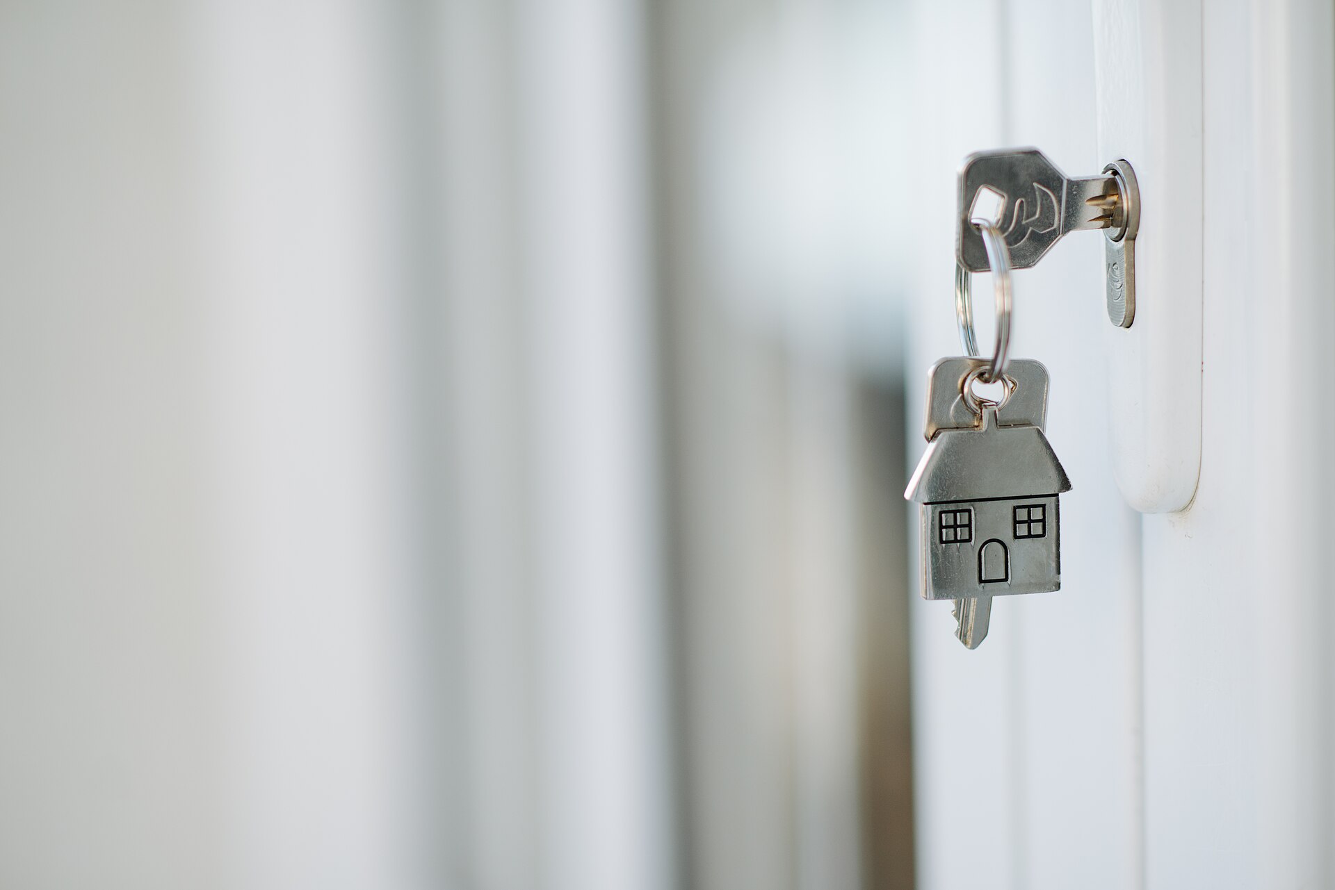 A house key with a small house keyring in a door